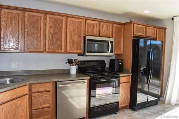 a kitchen with granite countertop a refrigerator stove and microwave