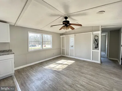 a view of an empty room with window and wooden floor