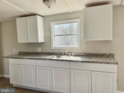 a kitchen with granite countertop white cabinets and a sink