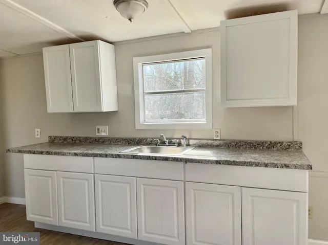 a kitchen with granite countertop white cabinets and a sink