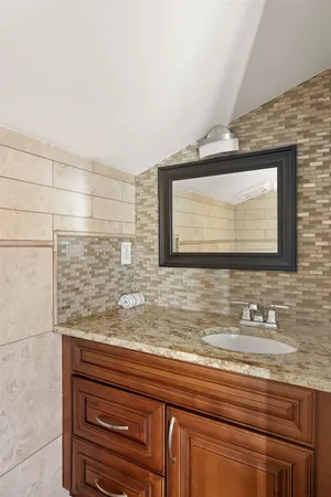 a bathroom with a granite countertop sink and a large mirror