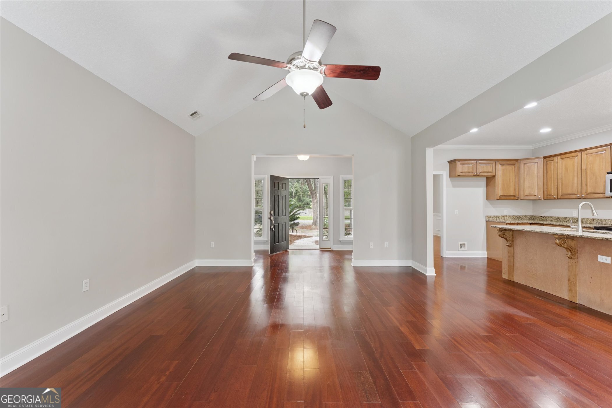 45 Veranda Trail Midway, GA 31320 - Photo 3 of 32 a view of an empty room with wooden floor and a kitchen