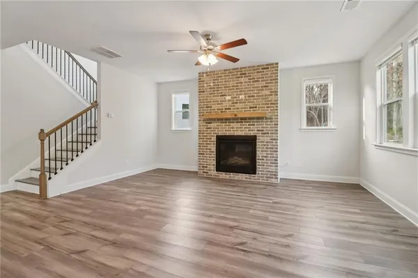 a view of an empty room with wooden floor a fireplace and a window