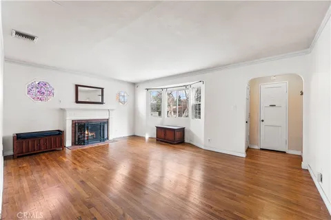 a view of a livingroom with fireplace wooden floor chandelier and windows