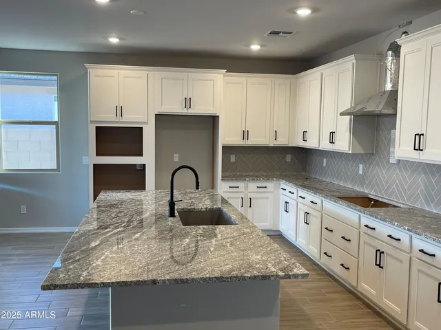 a kitchen with granite countertop white cabinets and stainless steel appliances