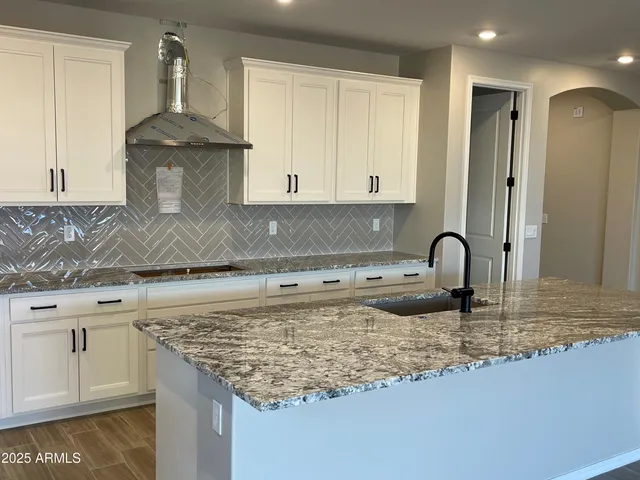 a kitchen with granite countertop a sink a stove and cabinets