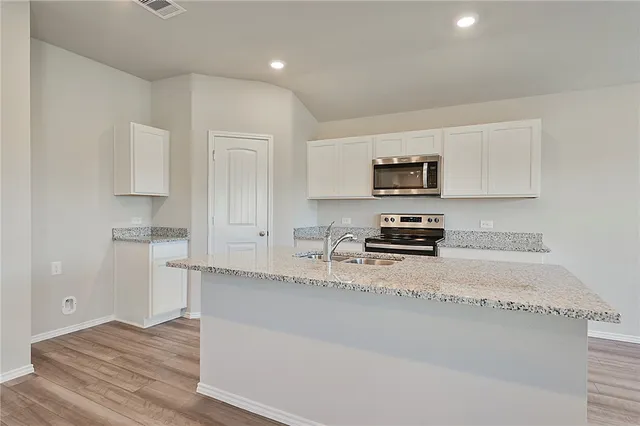 a kitchen with granite countertop a stove a sink and a microwave
