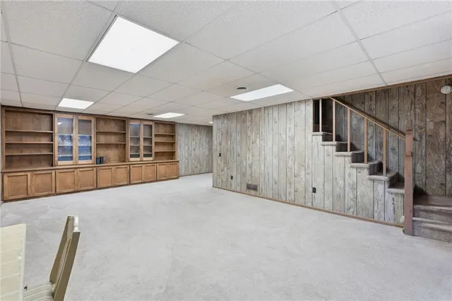 a view of an empty room with wooden floor and stairs