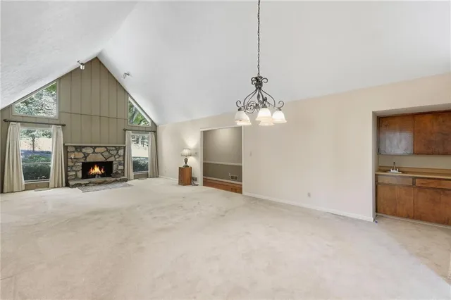 a view of a livingroom with a fireplace a chandelier and windows