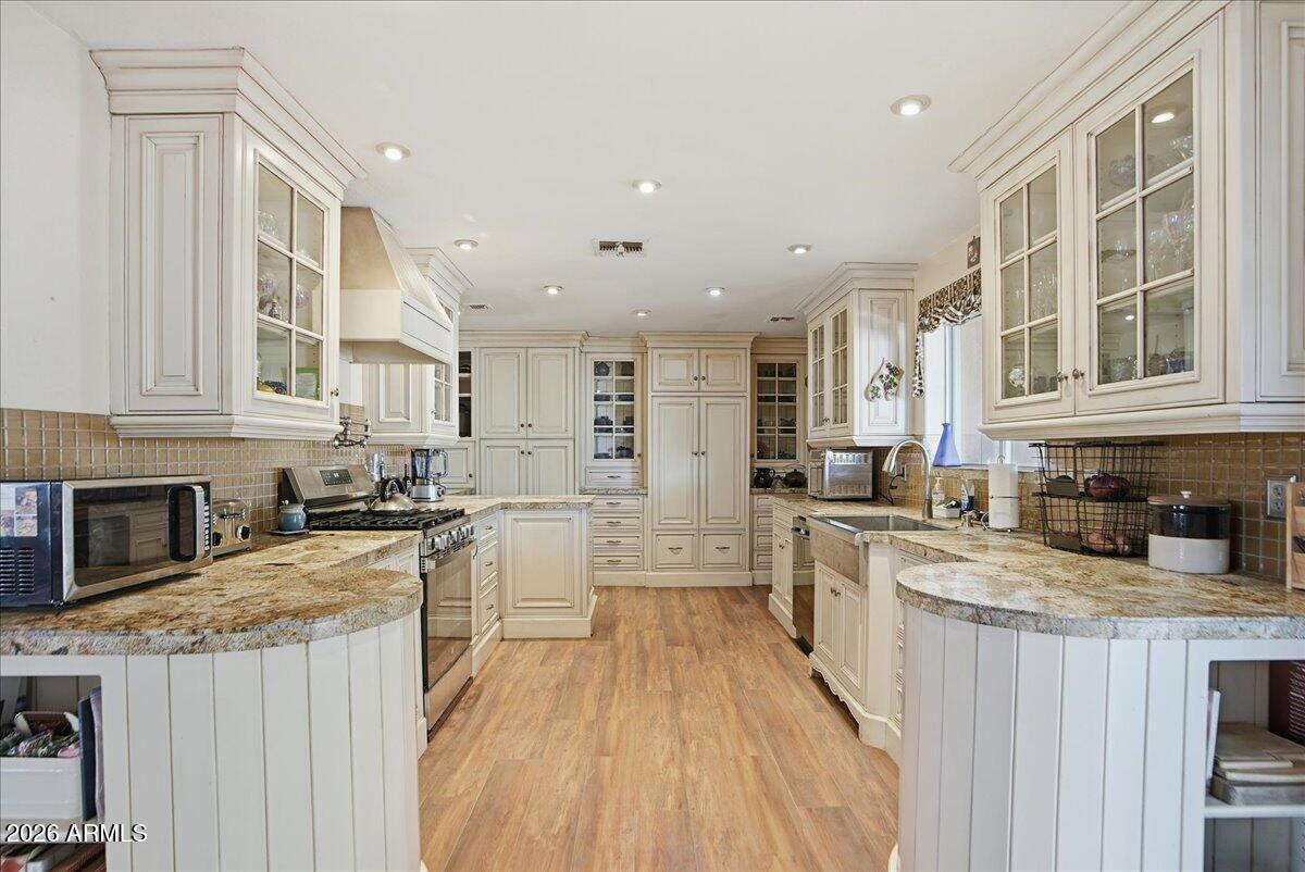 1414 West Ocotillo Road San Tan Valley, AZ 85140 - Photo 13 of 62 a large kitchen with stainless steel appliances granite countertop a stove top oven a sink dishwasher a dining table and chairs with wooden floor