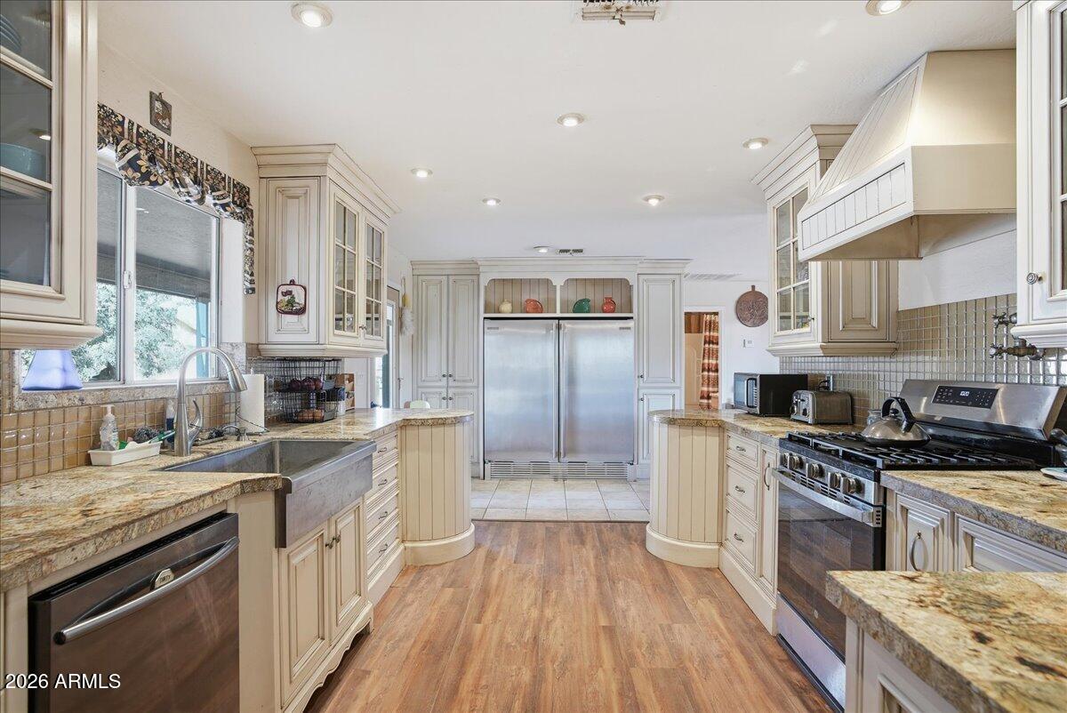 1414 West Ocotillo Road San Tan Valley, AZ 85140 - Photo 16 of 62 a kitchen with stainless steel appliances granite countertop a stove top oven a sink dishwasher a refrigerator and a cabinets with wooden floor