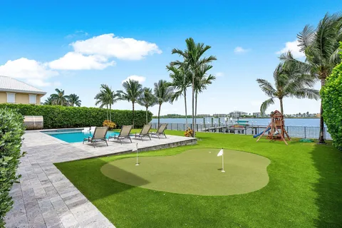 a view of a swimming pool and lounge chairs in back yard of a house