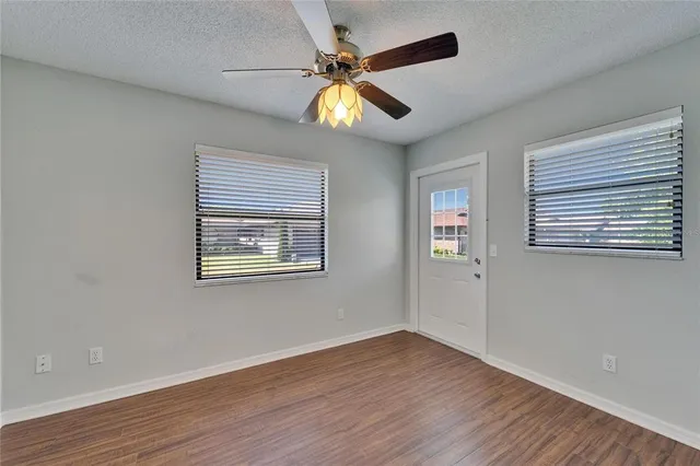 an empty room with windows and fan