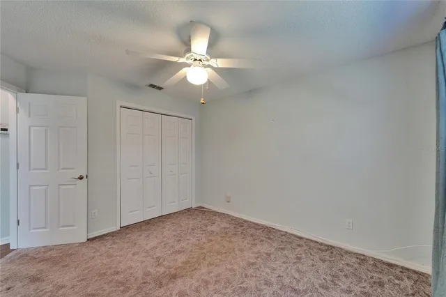 a view of an empty room with wooden floor and a ceiling fan