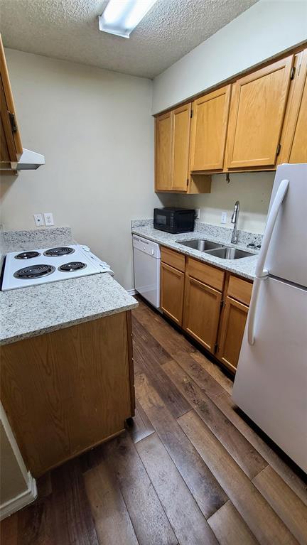 1907 Robbins Place, Unit 103 Austin, TX 78705 - Photo 3 of 5 Kitchen with white appliances, a textured ceiling, dark wood-type flooring, and wood finish cabinetry