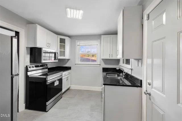a kitchen with granite countertop a stove sink and refrigerator