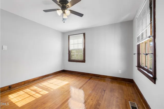 an empty room with windows and ceiling fan