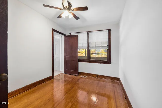 an empty room with wooden floor chandelier fan and windows