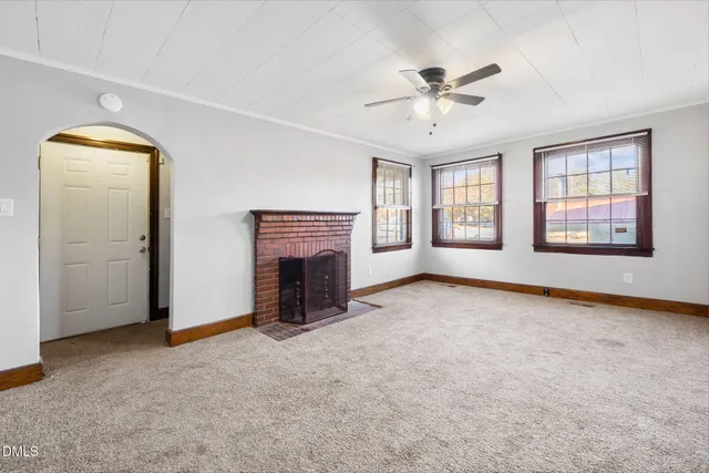 an empty room with windows and fireplace