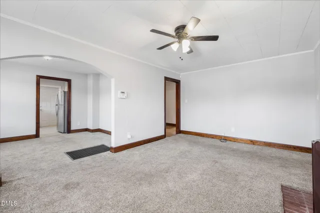a view of an empty room with chandelier fan