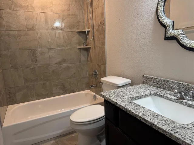 a bathroom with a granite countertop sink and a toilet