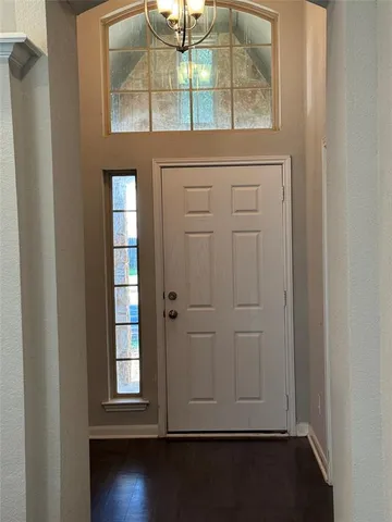 an empty room with wooden floor windows and entryway