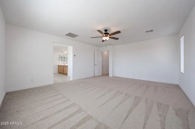 a view of an empty room with chandelier fan and windows
