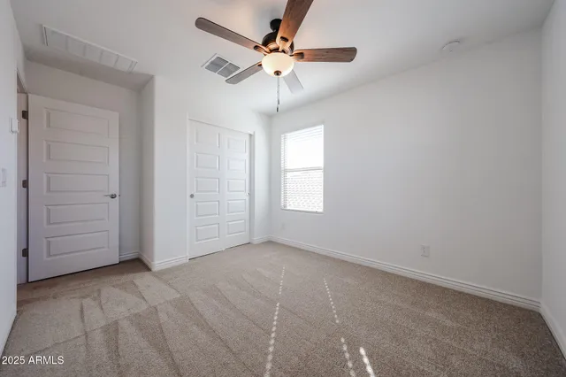 an empty room with closet and ceiling fan