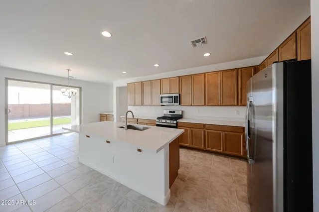 a large kitchen with kitchen island a large counter top stainless steel appliances and cabinets