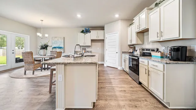 a kitchen with stainless steel appliances kitchen island granite countertop a stove top oven a sink a dining table and chairs with wooden floor