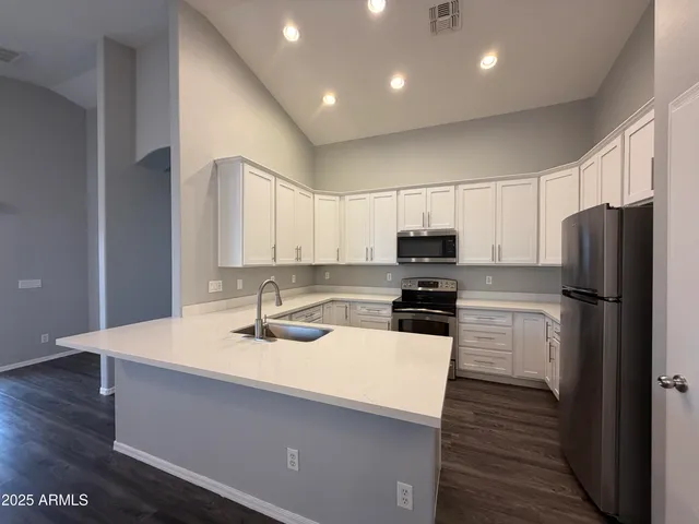 a kitchen with a sink a microwave a refrigerator and cabinets