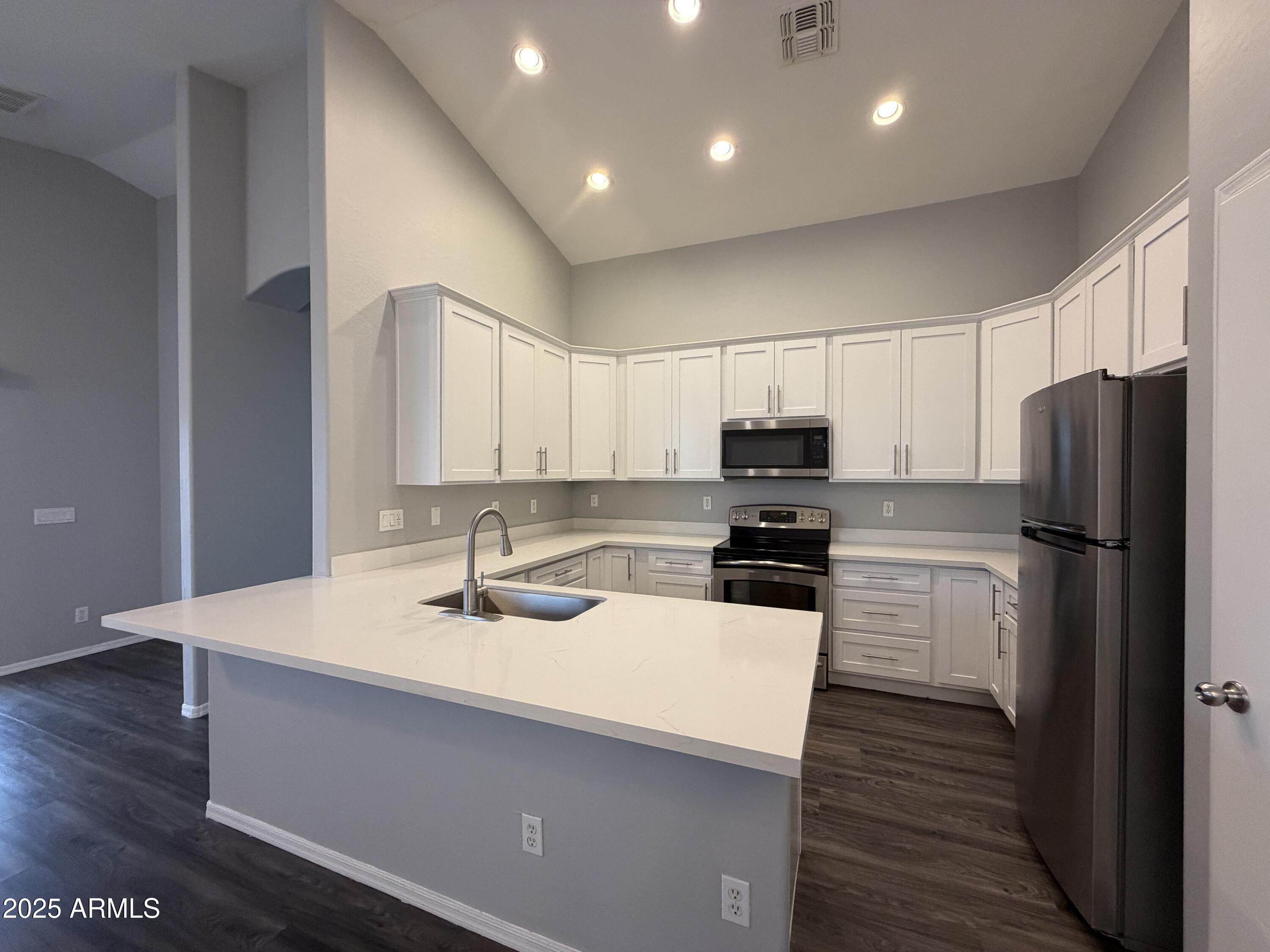 18123 North Madison Road Maricopa, AZ 85139 - Photo 2 of 26 a kitchen with a sink a microwave a refrigerator and cabinets