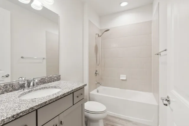 a bathroom with a granite countertop sink a toilet and shower