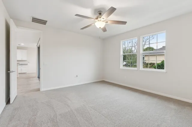an empty room with windows and ceiling fan