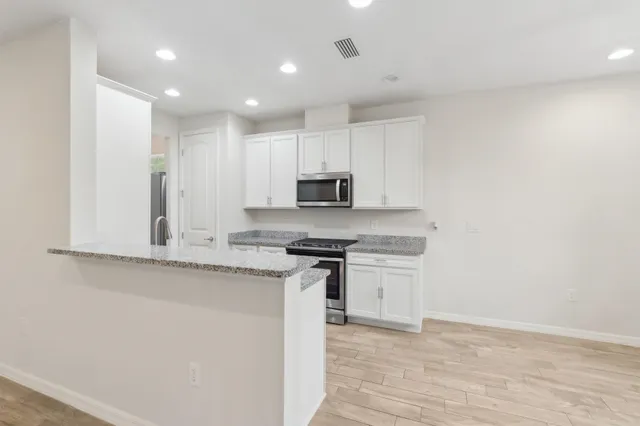 a kitchen with granite countertop white cabinets and stainless steel appliances