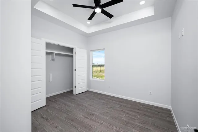 an empty room with wooden floor and ceiling fan