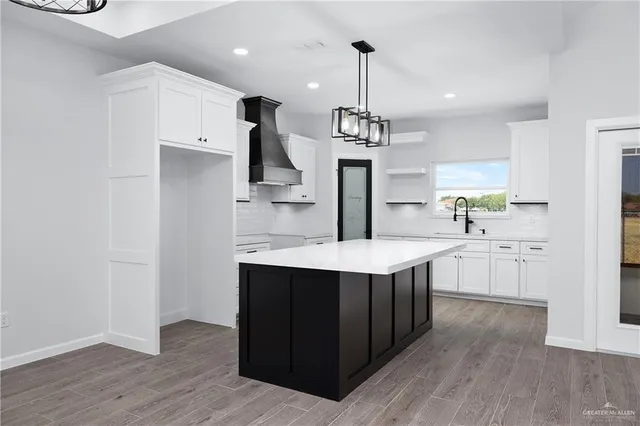 a kitchen with stainless steel appliances a sink a stove a refrigerator and island with wooden floor