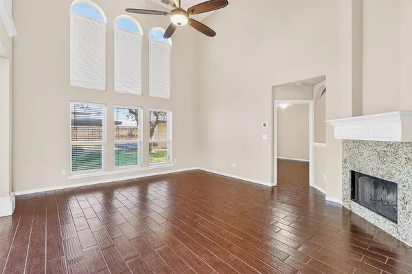 a view of an empty room with wooden floor and a fireplace