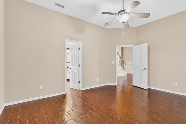 an empty room with wooden floor and ceiling fan