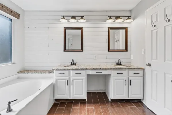 a spacious bathroom with a double vanity sink a mirror and a bathtub