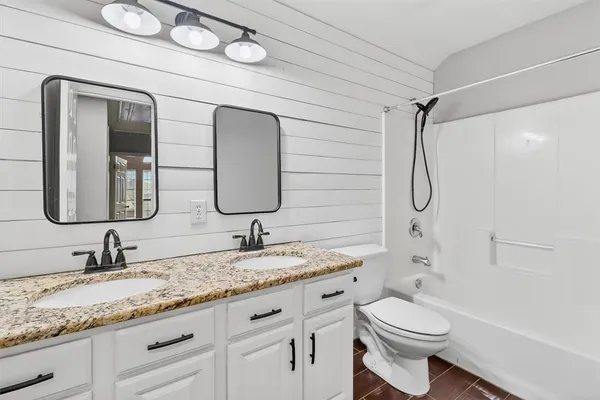 a bathroom with a granite countertop sink mirror vanity and toilet