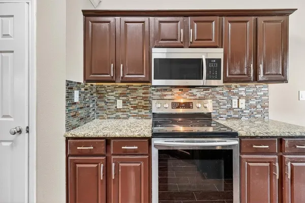 a kitchen with granite countertop a stove sink and microwave