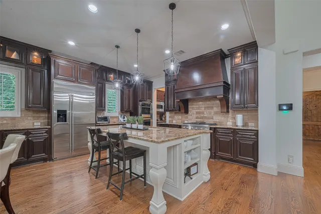 a kitchen with stainless steel appliances granite countertop a stove a refrigerator a oven a sink a dining table and chairs with wooden floor