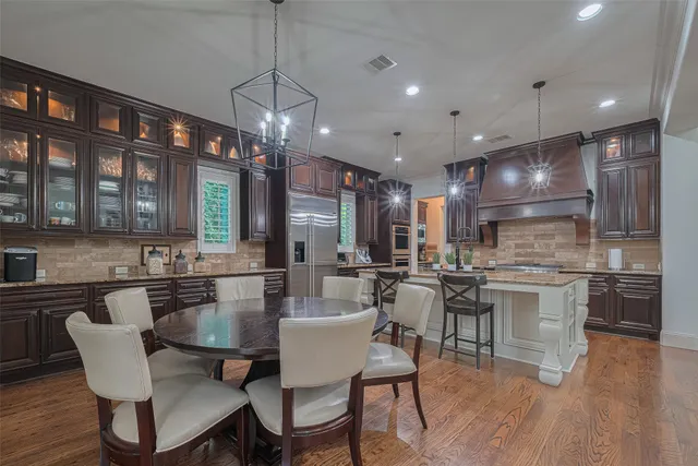 a kitchen with a dining table chairs wooden floor and appliances
