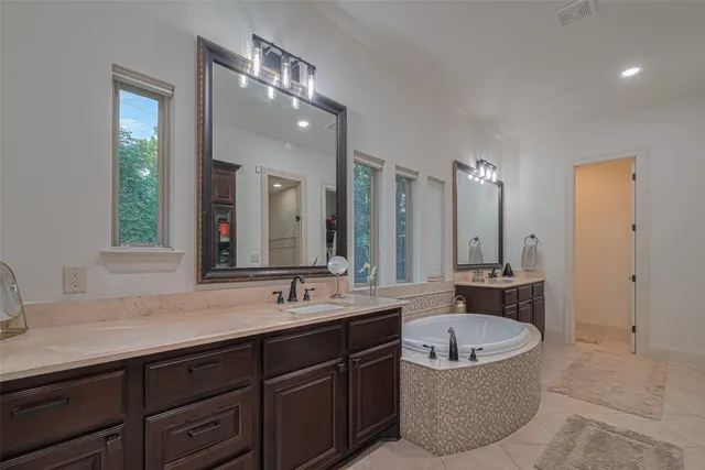 a bathroom with a sink double vanity granite tub shower and mirror