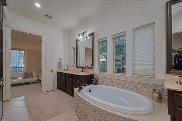 a bathroom with a tub a sink and a large mirror