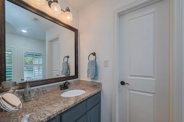 a bathroom with a granite countertop sink a mirror and a vanity