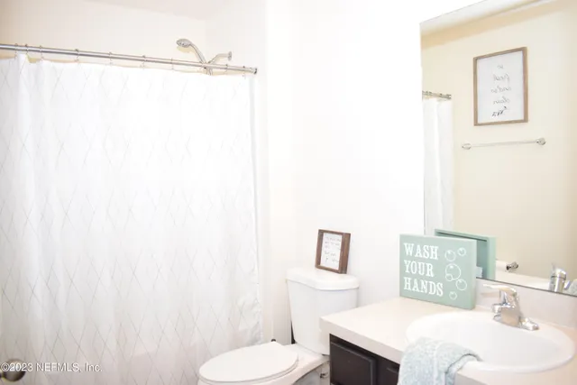 a bathroom with a sink a toilet and shower curtain