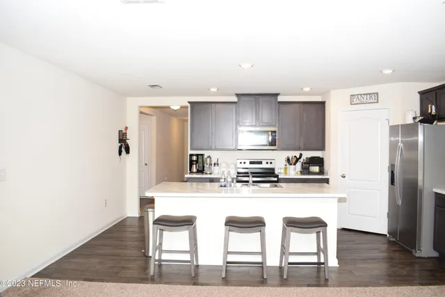 a kitchen with stainless steel appliances granite countertop a table chairs sink and cabinets