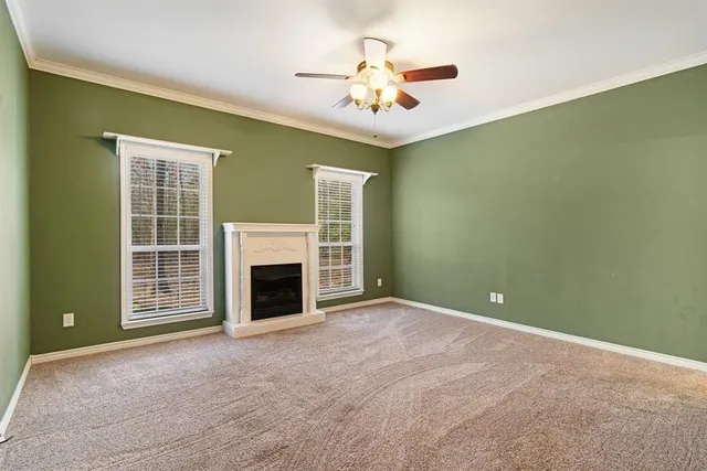 an empty room with a fireplace and a ceiling fan
